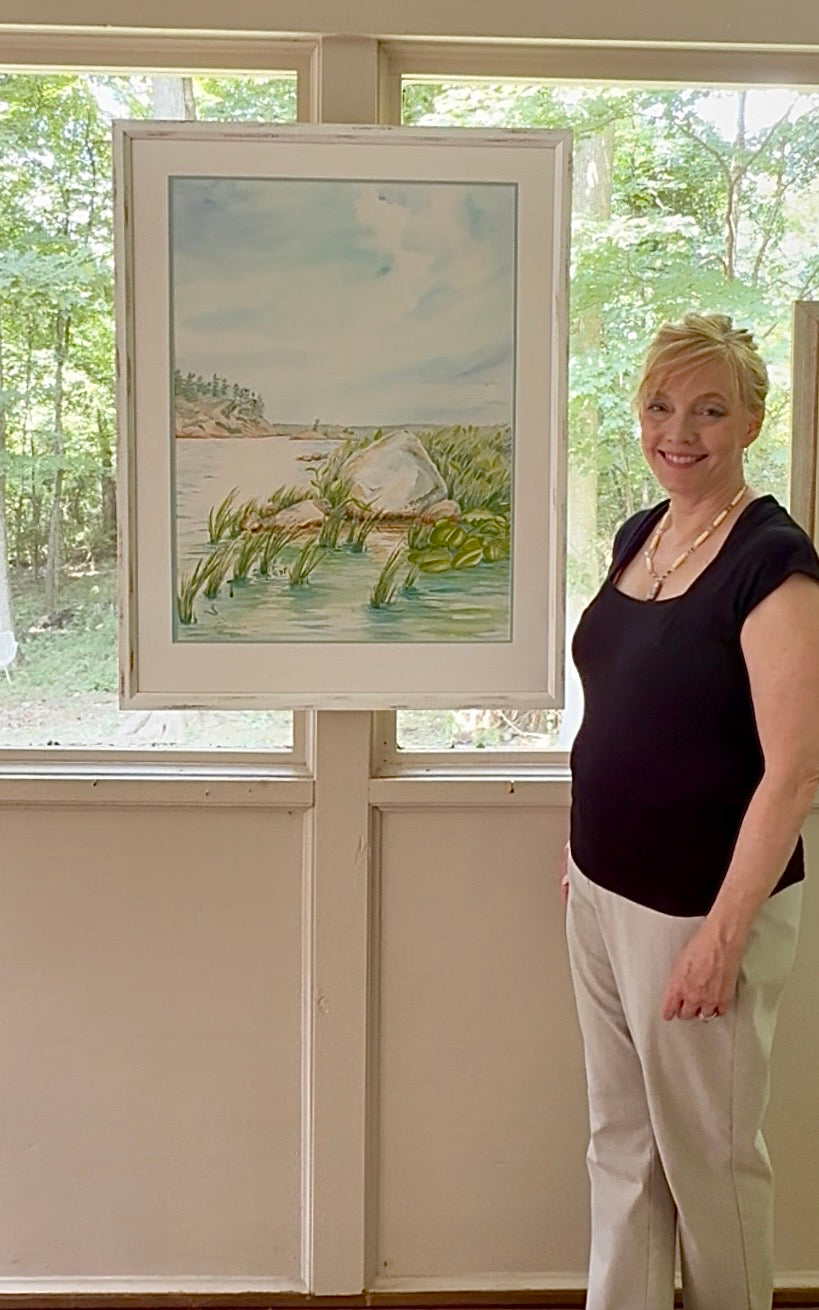 Artist Pamela Hallock with her original framed watercolor "Granite and Wind," inspired by the granite shoreline of Georgian Bay, Ontario.