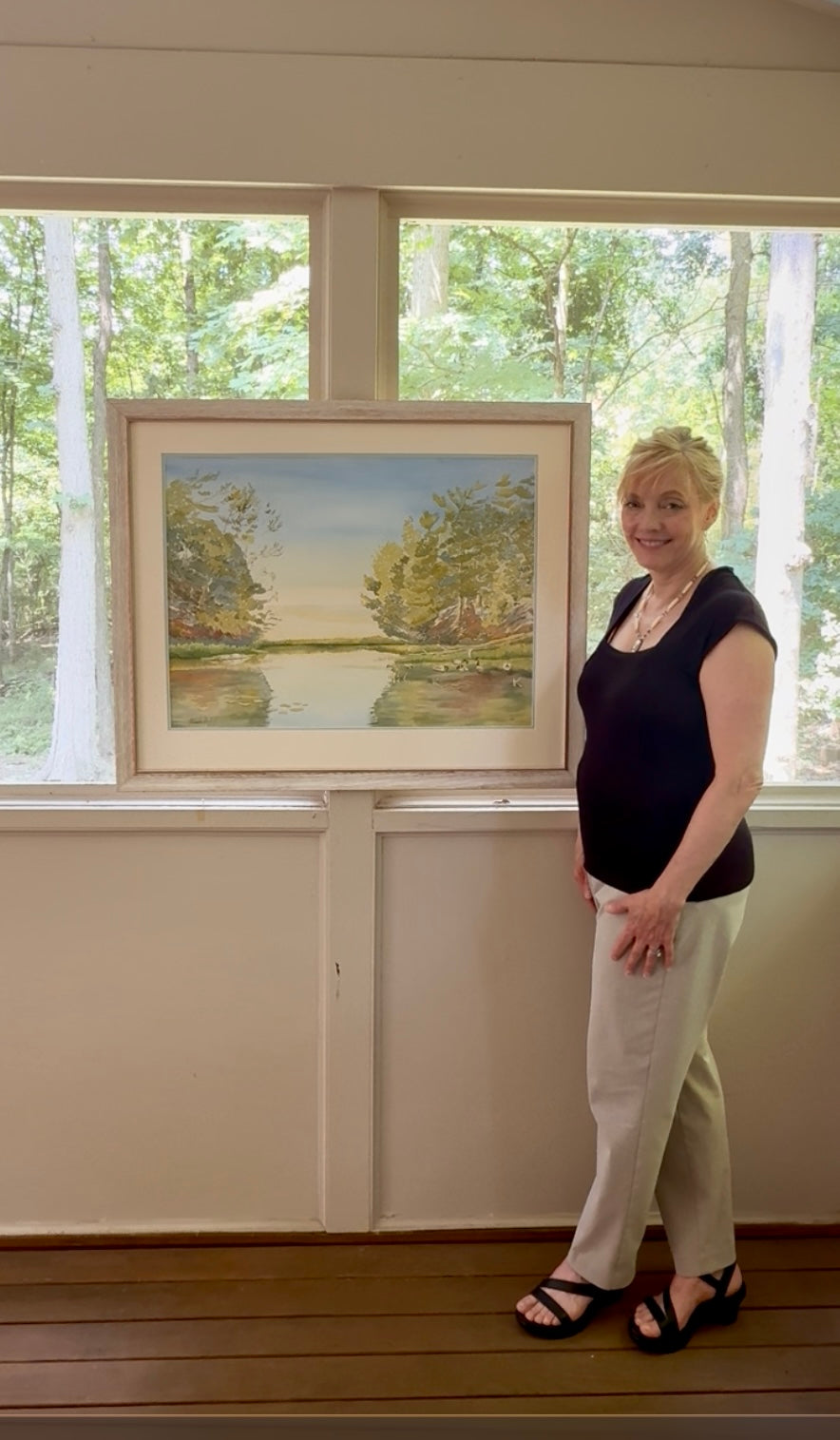 Artist Pamela Hallock with her original watercolor, Turtle Bay. Inspired by the tranquil shoreline of Lake Huron, this one-of-a-kind painting celebrates the quiet beauty of Georgian Bay and the peaceful moments found in nature.