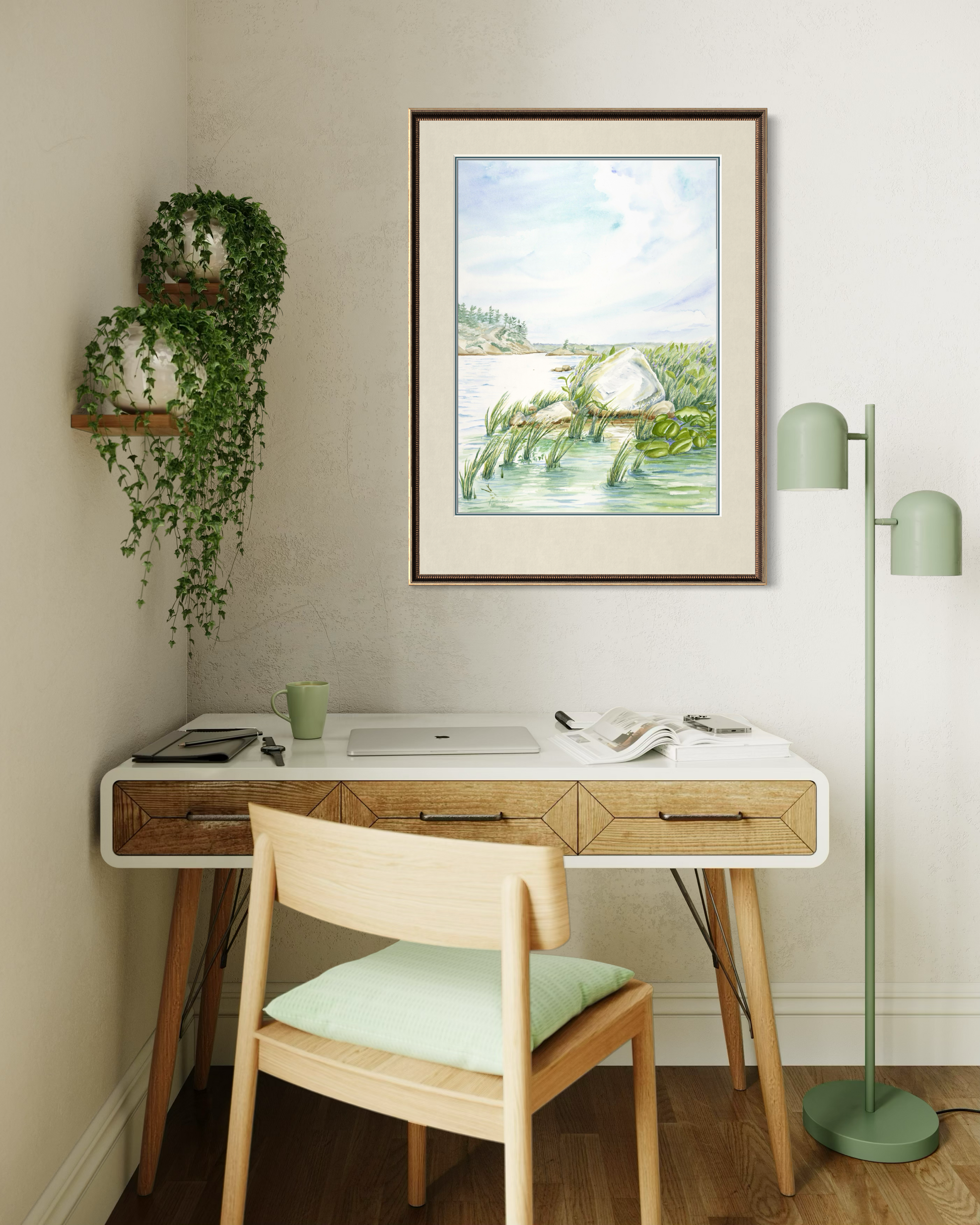 Framed Granite and Wind watercolor print of Georgian Bay landscape displayed above a desk in a bright workspace.
