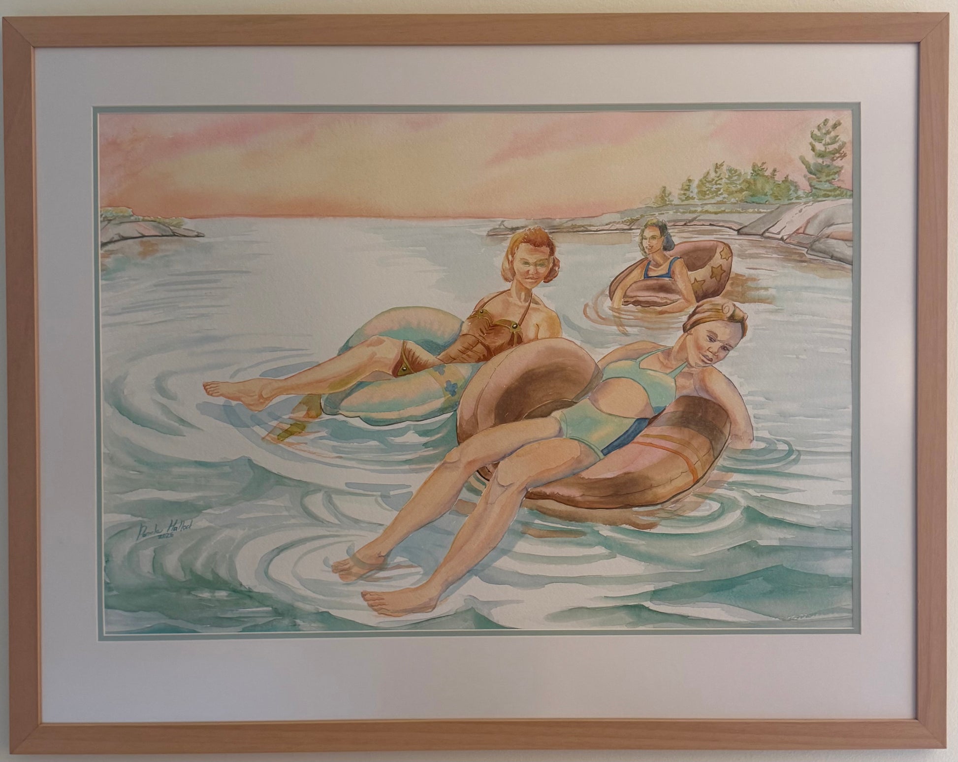 Framed original watercolor painting, Pink Skies, by Pamela Hallock featuring three women relaxing in inner tubes on the calm waters of Georgian Bay beneath a soft pink evening sky.