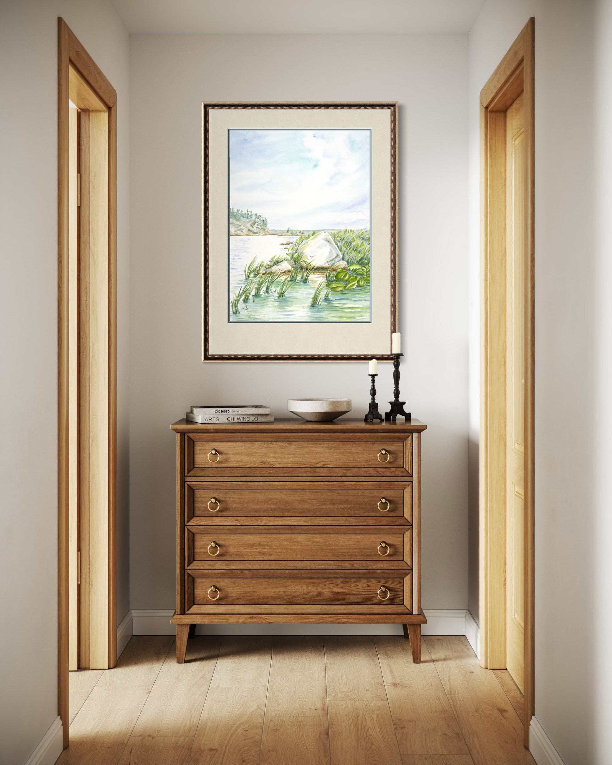Framed Granite and Wind watercolor print of Georgian Bay shoreline displayed above a wooden dresser in a hallway interior.